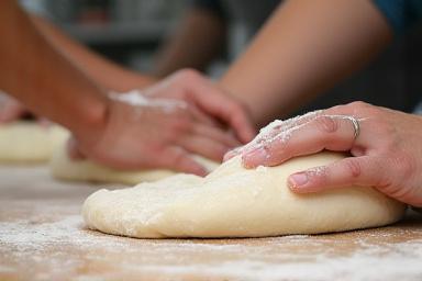 Partecipanti a un corso di cucina che impastano la pizza